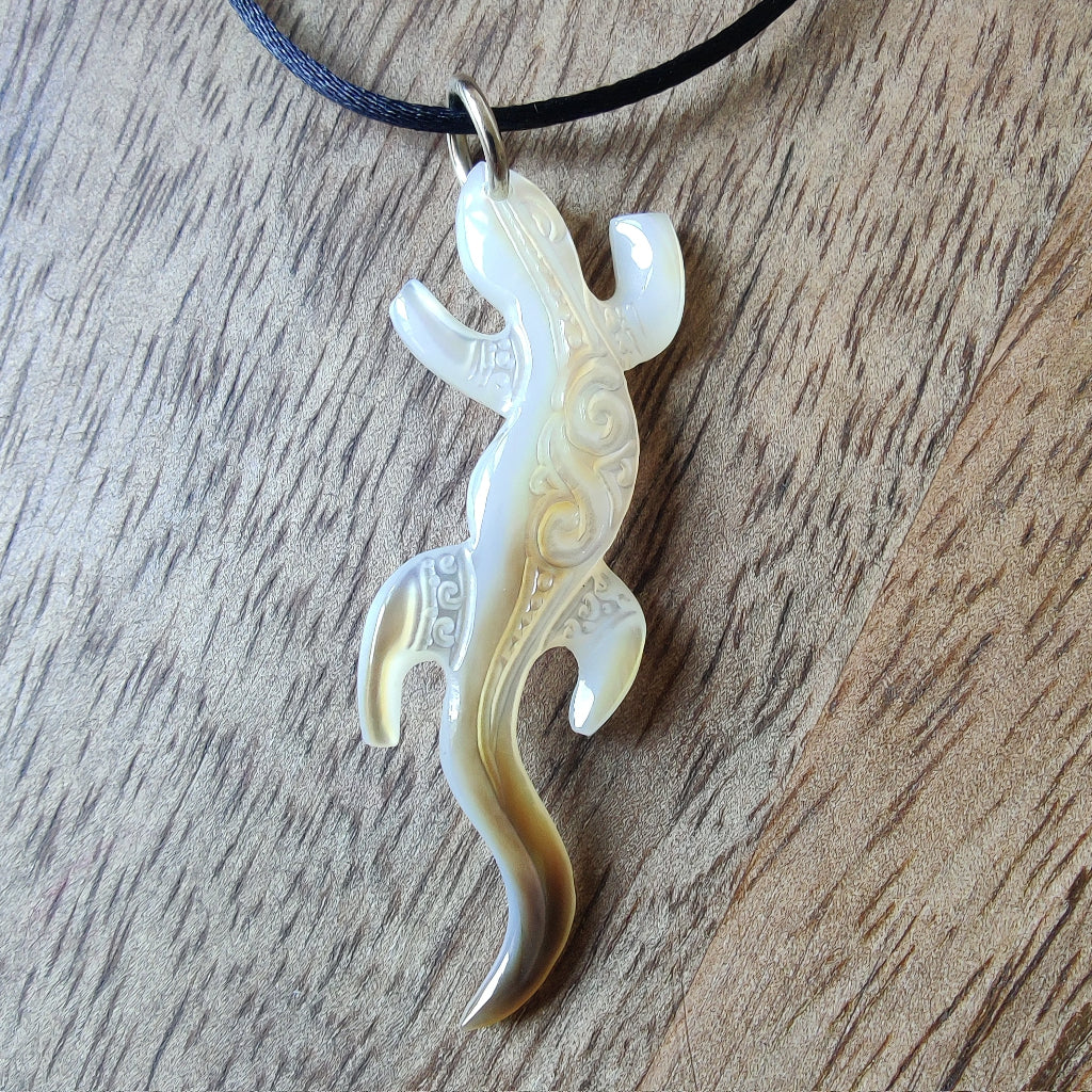 Pendentif geckko margouillat en nacre gravée de Tahiti. Bijou polynésien artisanal monté sur lien noir ajustable.