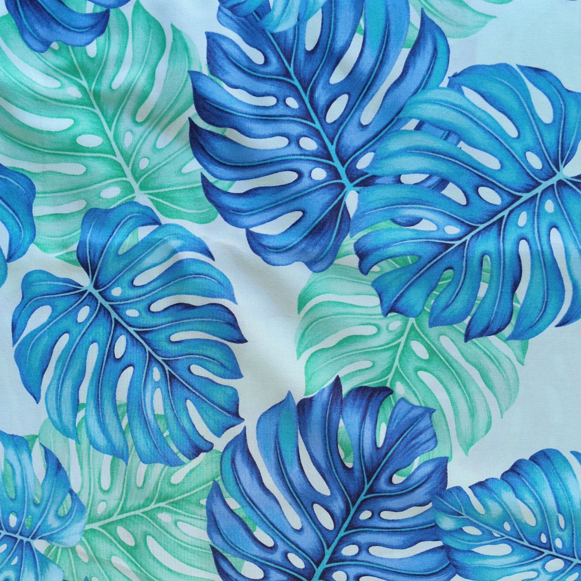 Détail motif Monstera aquarelle vert tendre bleu délicat sur fond bleu clair 100% coton