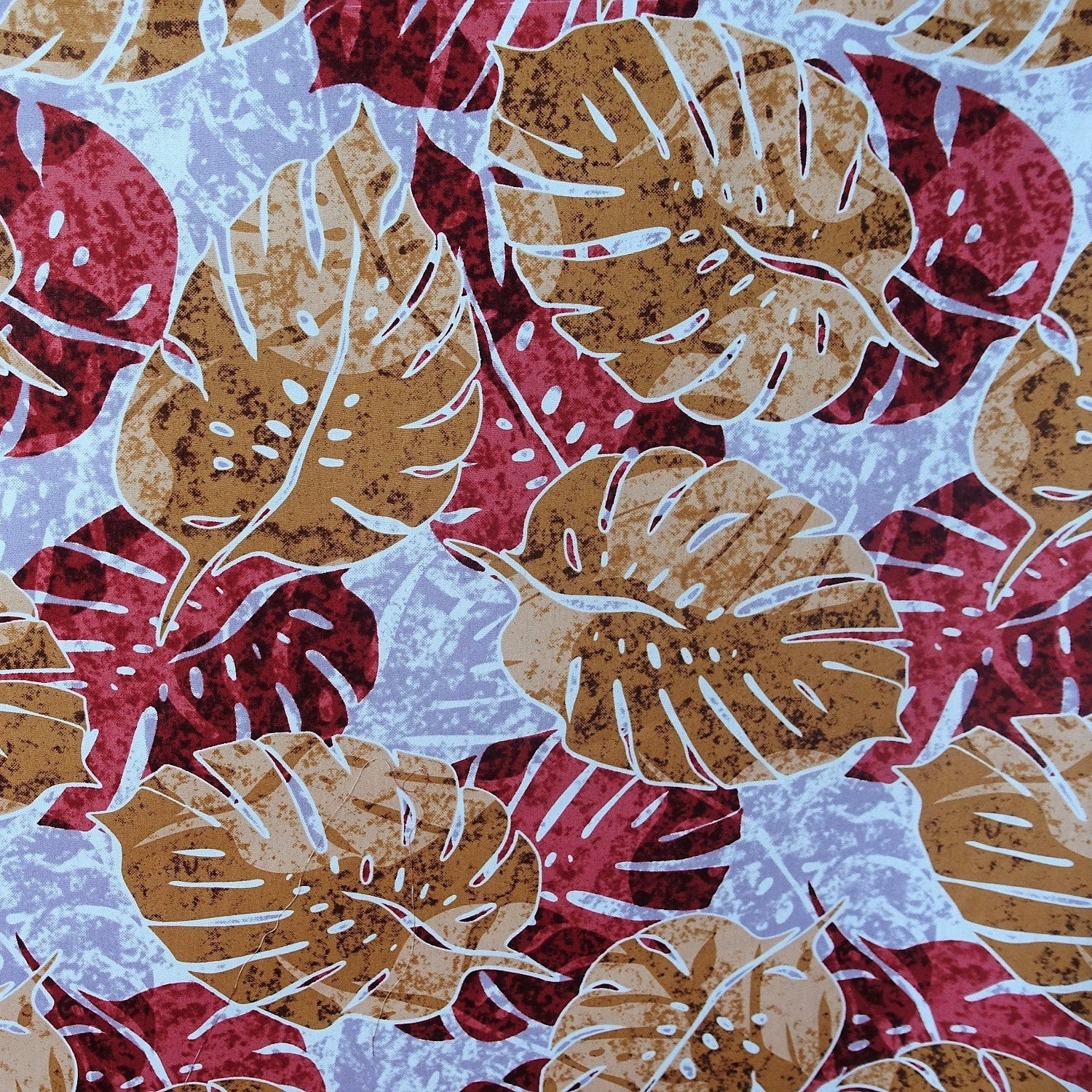Détail motif Monstera marron caramel bordeaux sur fond bleu gris moucheté 100% coton