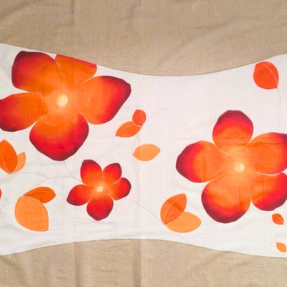 Détails du paréo tahitien en voile de coton, peint à la main à Tahiti, motifs frangipaniers orange sur fond marron et blanc. Paréo artisanal traditionnel
