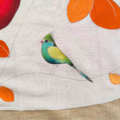 zoom sur oiseau du paréo tahitien en voile de coton, peint à la main à Tahiti, motifs frangipaniers orange sur fond marron et blanc. Paréo artisanal traditionnel