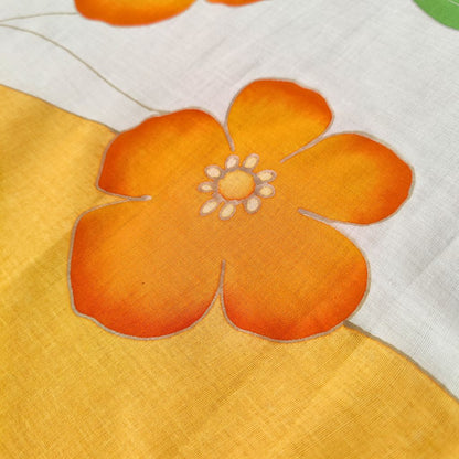 zoom du paréo tahitien en voile de coton, peint à la main à Tahiti, motifs hibiscus orange et blanc. Paréo artisanal traditionnel