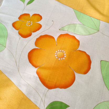 Détails du paréo tahitien en voile de coton, peint à la main à Tahiti, motifs hibiscus orange et blanc. Paréo artisanal traditionnel
