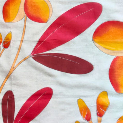 gros plan sur le paréo tahitien en voile de coton, peint à la main à Tahiti, motifs frangipaniers orange sur fond rouge et blanc. Paréo artisanal traditionnel