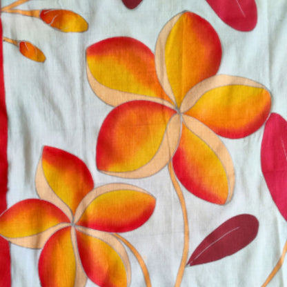 zoom sur le paréo tahitien en voile de coton, peint à la main à Tahiti, motifs frangipaniers orange sur fond rouge et blanc. Paréo artisanal traditionnel