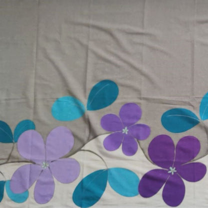 Détails du paréo tahitien en voile de coton, peint à la main à Tahiti, motifs tiarés violet et bleu sur fond gris et blanc. Paréo artisanal traditionnel