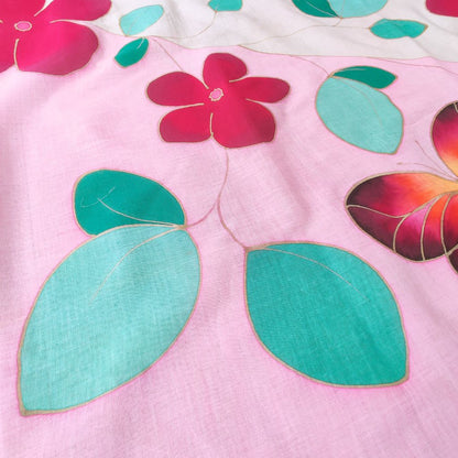 Détails du paréo tahitien en voile de coton, peint à la main à Tahiti, motifs fleurs de tiaré rose, feuillage vert et papillon sur fond blanc et rose pastel. Paréo artisanal traditionnel