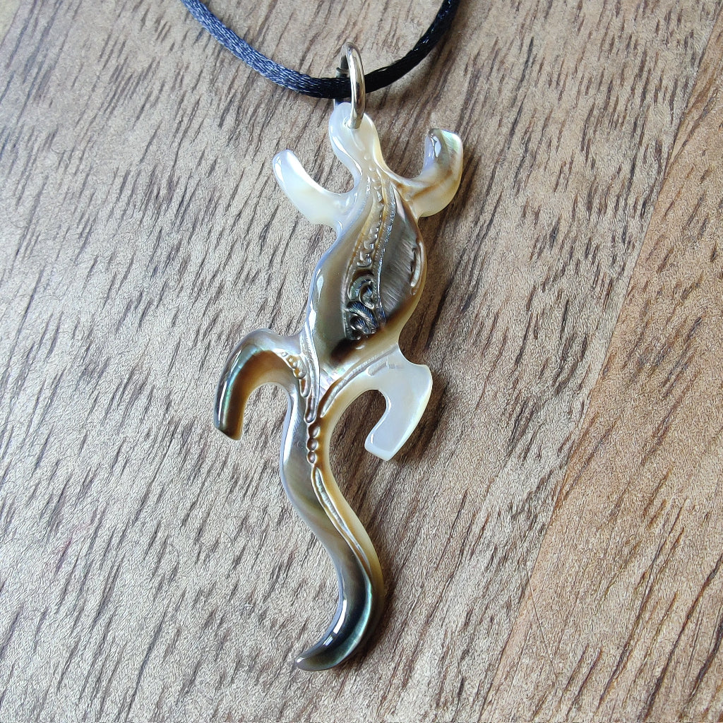 Pendentif geckko margouillat en nacre gravée de Tahiti. Bijou polynésien artisanal monté sur lien noir ajustable.