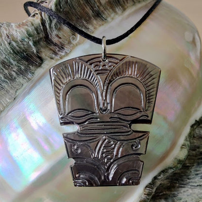 Pendentif Tiki en nacre gravée de Tahiti, monté sur lien noir ajustable. Bijou polynésien symbole de guerrier protecteur