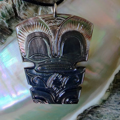 Pendentif Tiki en nacre gravée de Tahiti, monté sur lien noir ajustable. Bijou polynésien symbole de guerrier protecteur