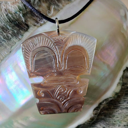 Pendentif Tiki en nacre gravée de Tahiti, monté sur lien noir ajustable. Bijou polynésien symbole de guerrier protecteur