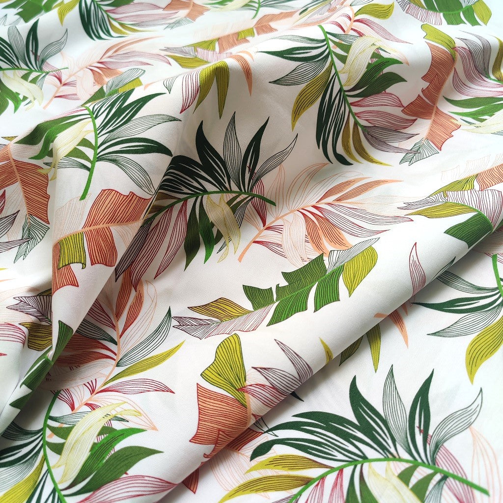 Tissu tahitien en coton, motifs feuilles de bananiers et fougères sur fond blanc lumineux. idéal pour coudre robe, chemise ou accessoires.