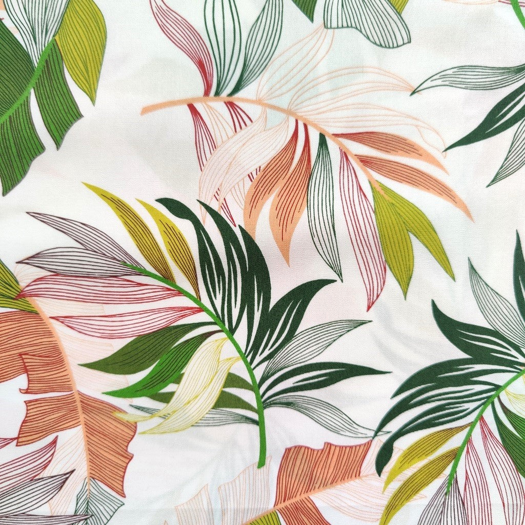Tissu tahitien en coton, gros plan des  motifs feuilles de bananiers et fougères sur fond blanc lumineux. Edition limitée - aucun réassort.
