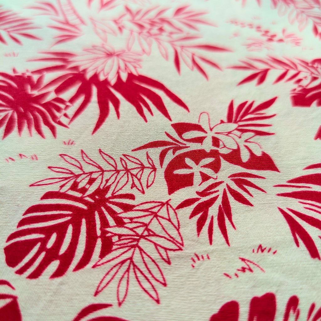 Zoom sur tissu tahitien en coton, cocotiers et feuillages rouge et beige. Edition limitée - aucun réassort