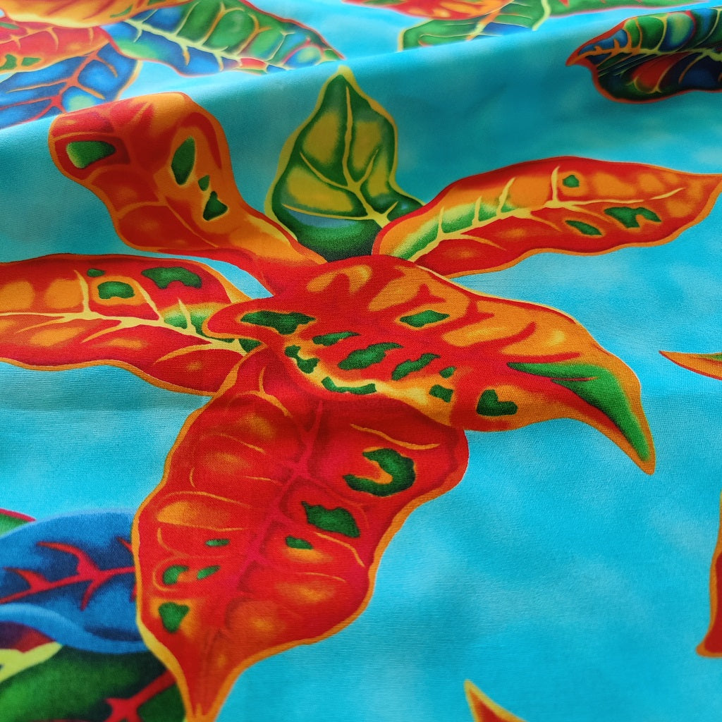 Tissu tahitien en coton, motifs crotons orange et vert sur fond bleu turquoise. Tissu exclusif - dernier coupon.