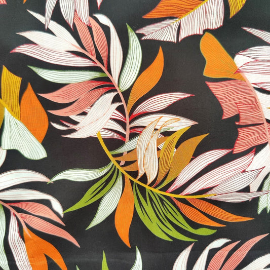 Tissu tahitien en coton, gros plan sur motifs feuilles de bananiers et fougères sur fond noir intense. Stock limité - aucun réassort.