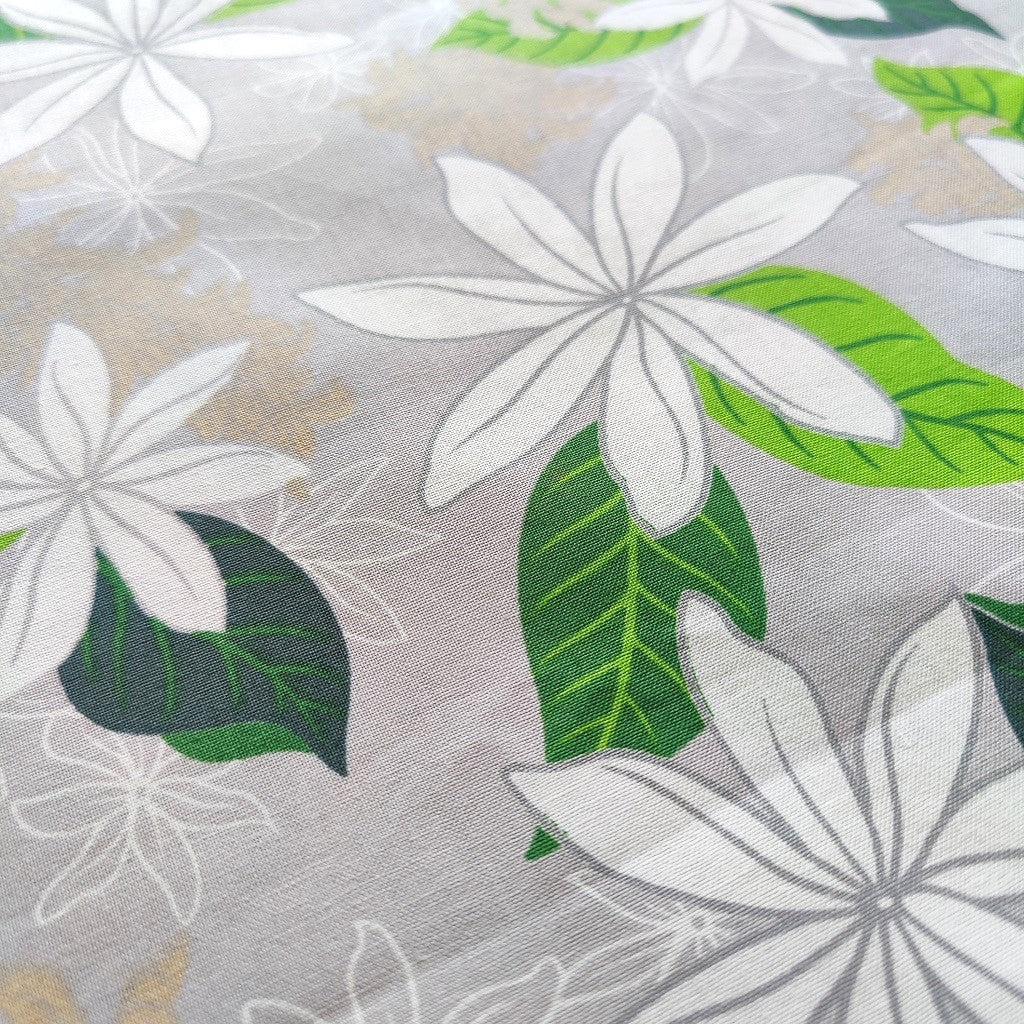 Tissu tahitien en coton, zoom sur les motifs fleurs de tiarés blanches sur fond gris perle. Métrage limité sur Couleurs du fénua