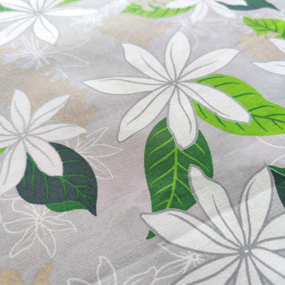 Tissu tahitien en coton, zoom sur les motifs fleurs de tiarés blanches sur fond gris perle. Métrage limité sur Couleurs du fénua