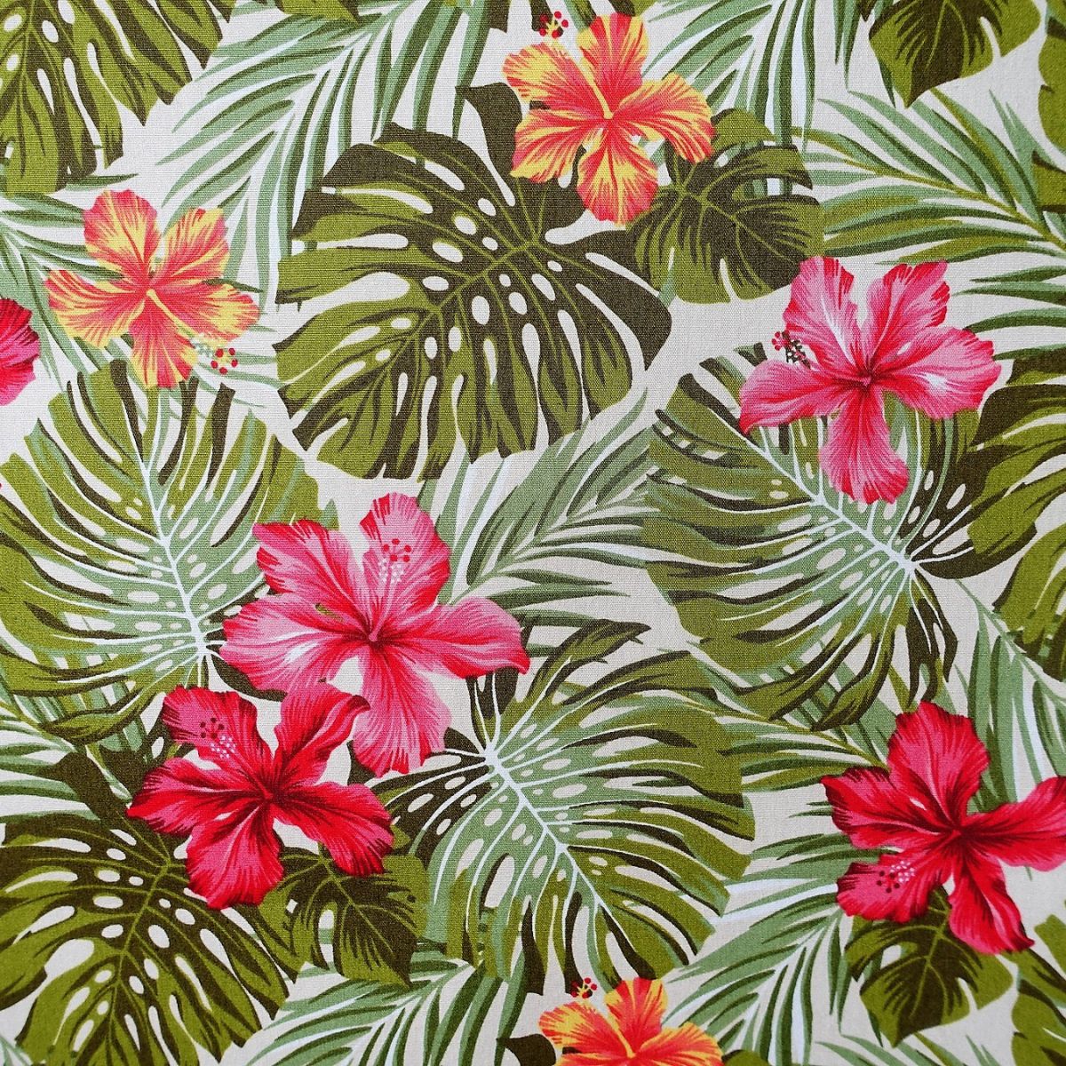 Tissu tahitien en coton, détails des motifs hibiscus et monstera, couleurs rose et vert sur fond beige. Edition limitée