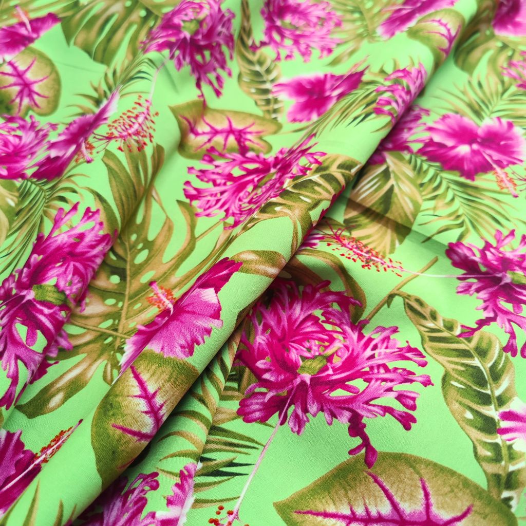 Tissu tahitien en coton motifs hibiscus rose de Chine et monstera, rose fuschia sur fond vert anis. Métrage limité