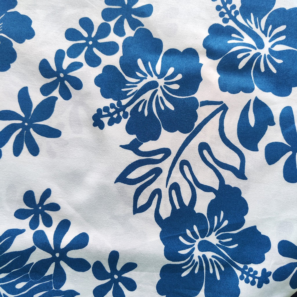 Zoom sur tissu tahitien en coton, fleurs hibiscus et tiaré bleu sur fond blanc lumineux - Edition limitée aucun réassort.