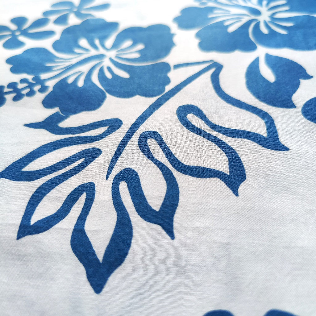 Tissu tahitien en coton, fleurs hibiscus et tiaré bleu sur fond blanc lumineux - gros plan sur les motifs du tissu