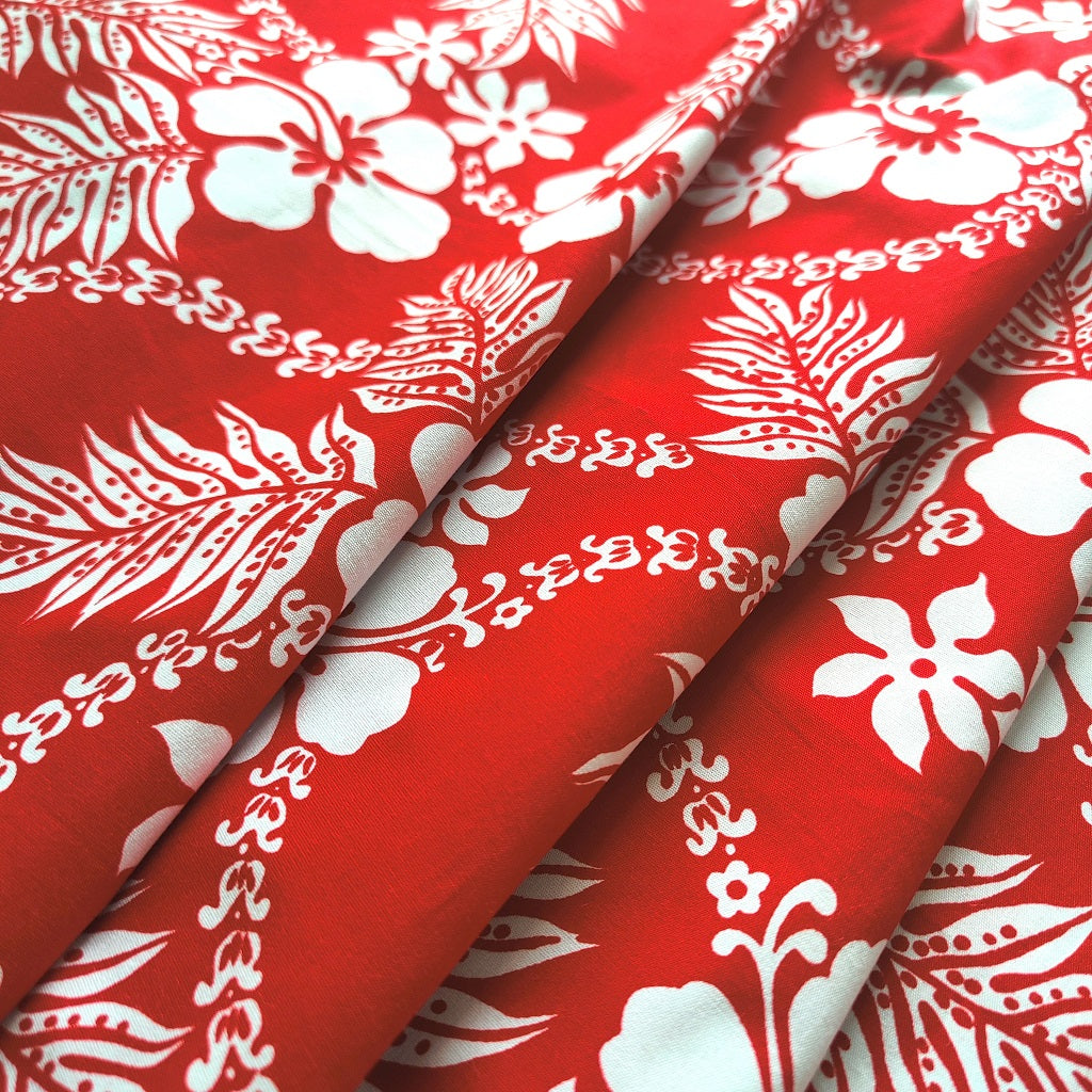 Tissu tahitien en coton, motifs hibiscus, fougères et tiarés blanches sur fond rouge vif. Tissu plié. Edition limitée, dernier coupon.
