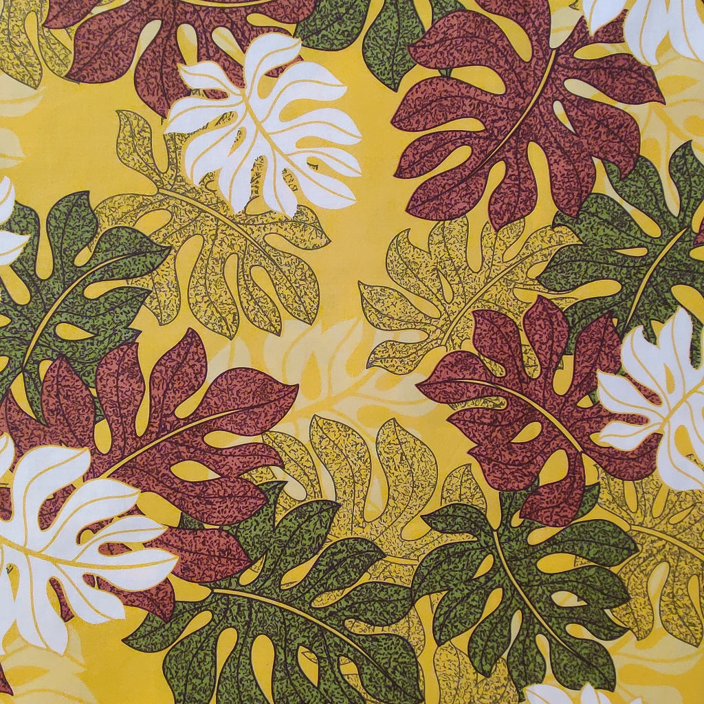 Tissu tahitien en coton, zoom sur le motif monsteras marron vert et blanc sur fond jaune lumineux. Stock limité.