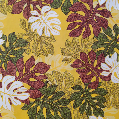 Tissu tahitien en coton, zoom sur le motif monsteras marron vert et blanc sur fond jaune lumineux. Stock limité.