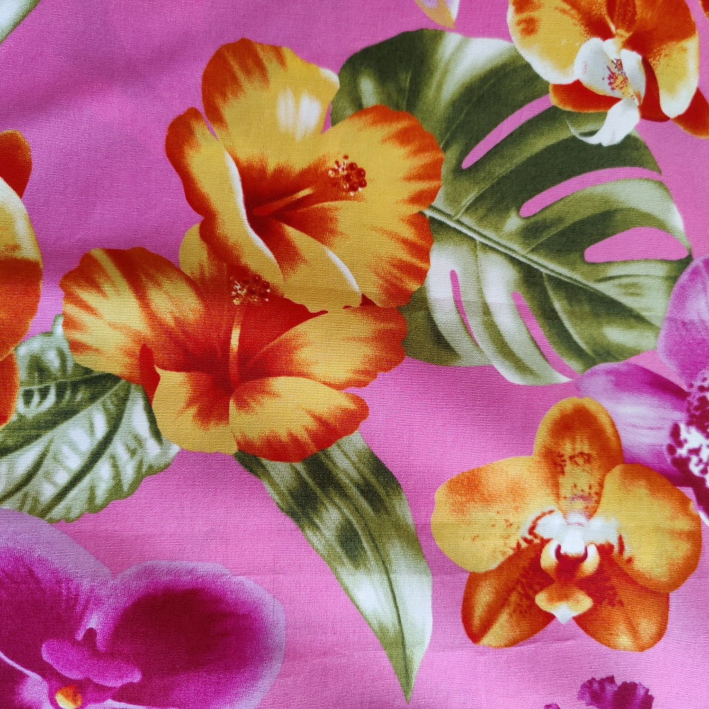 Tissu tahitien en coton, zoom sur les motifs orchidées et hibiscus orange et violet sur fond rose. stock limité. Vendu en coupon.